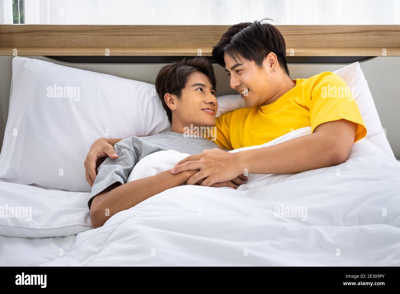 Felice omosessuale asiatico uomini gay coppia maschile mentendo e abbracciando a letto. LGBT e concetto di diversità sessuale. Foto Stock