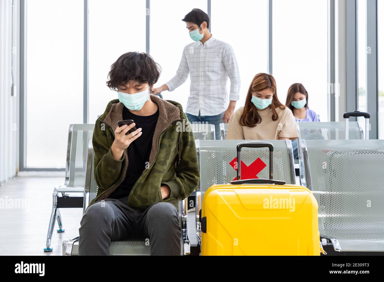 Viaggiatori che indossano maschera protettiva in aeroporto internazionale, durante la pandemia Covid-19, sicurezza con protocollo di distanza sociale, nuovo normale viaggio concep Foto Stock
