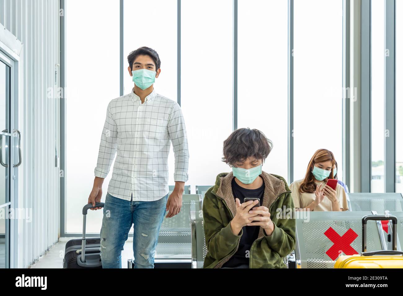 Viaggiatori che indossano maschera protettiva in aeroporto internazionale, durante la pandemia Covid-19, sicurezza con protocollo di distanza sociale, nuovo normale viaggio concep Foto Stock