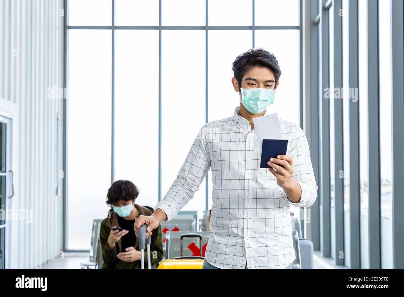 Viaggiatore che indossa una maschera protettiva in aeroporto, durante la pandemia di Covid-19, con protocollo di allontanamento sociale. Controllo del passaporto e del documento da preparare al t Foto Stock