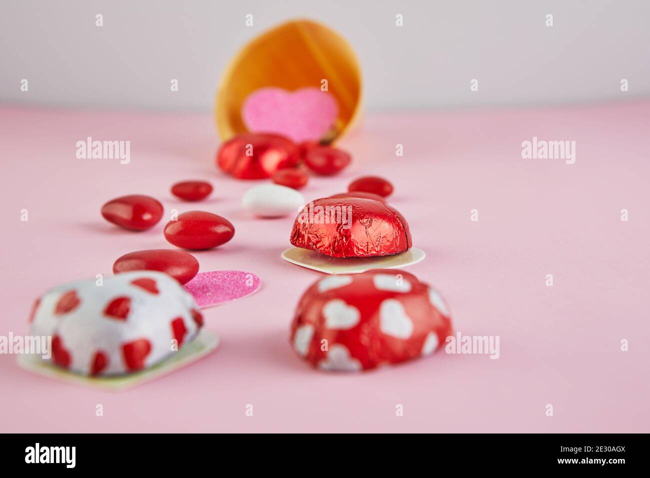 Carta di San Valentino con cuori di caramelle su sfondo cono gelato su sfondo rosa. Messa a fuoco selettiva. Foto Stock
