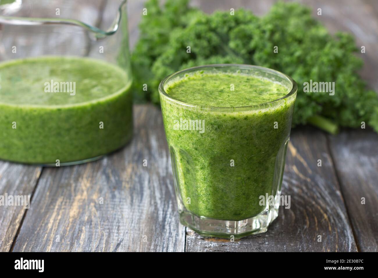Frappè verdi con kale, banana e limone. Su un tavolo di legno. Fuoco selettivo. Cibo sano di dieta Foto Stock