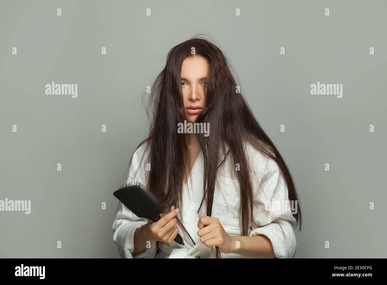 Donna malinconia che combatte i suoi capelli aggrovigliati al mattino, cura dei capelli e concetto di problema dei capelli Foto Stock
