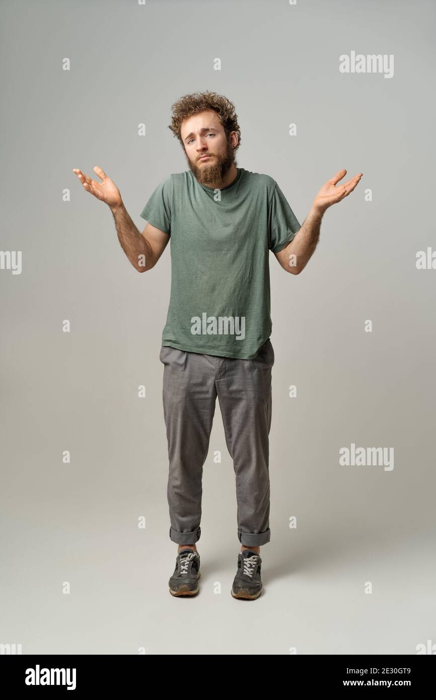 Non so gesturing con entrambe le mani. Bell'uomo con capelli ricci isolati su sfondo bianco. Ritratto di giovane confuso su sfondo bianco Foto Stock