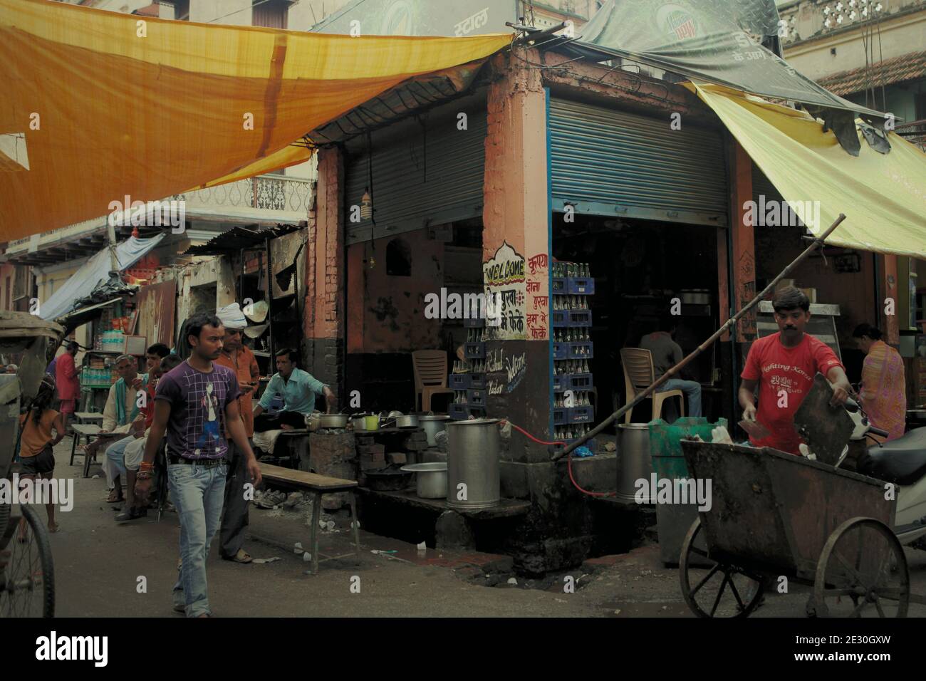 Le attività della gente su un incrocio di vicoli, dove un negozio di cibo di strada si trova a Varanasi, India. Foto Stock