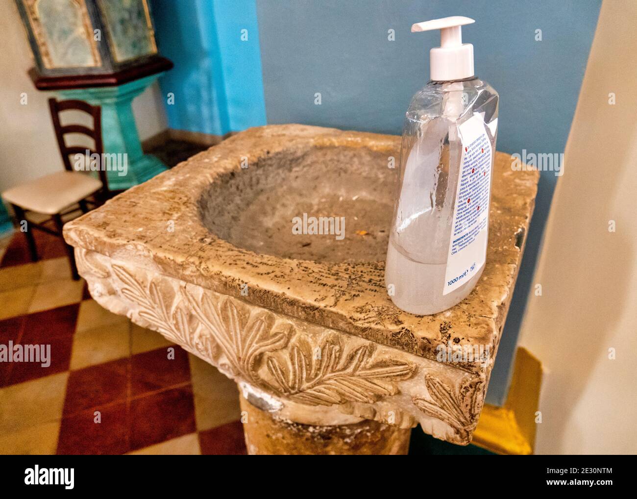 Vuota acqua sacra medievale nella Chiesa di San Salvatore in Silvi Paese, Italia. L'acqua Santa viene sostituita con un igienizzatore per le mani grazie al Covid-19 Foto Stock