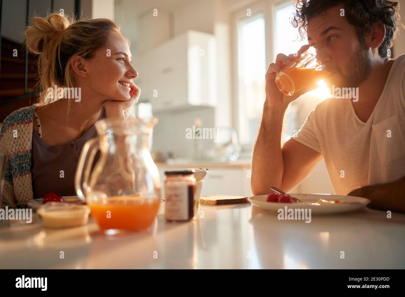 Una giovane coppia innamorata si rilassa al tavolo dopo la prima colazione in una bella giornata di sole a casa. Rapporto, amore, insieme, colazione Foto Stock