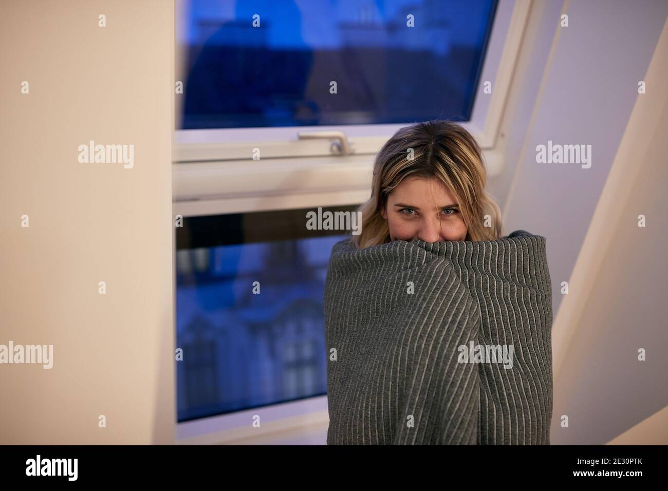 Una giovane ragazza coperta dalla coperta che posa per una foto su una bella mattina presto a casa. Mattina, a casa, di routine Foto Stock