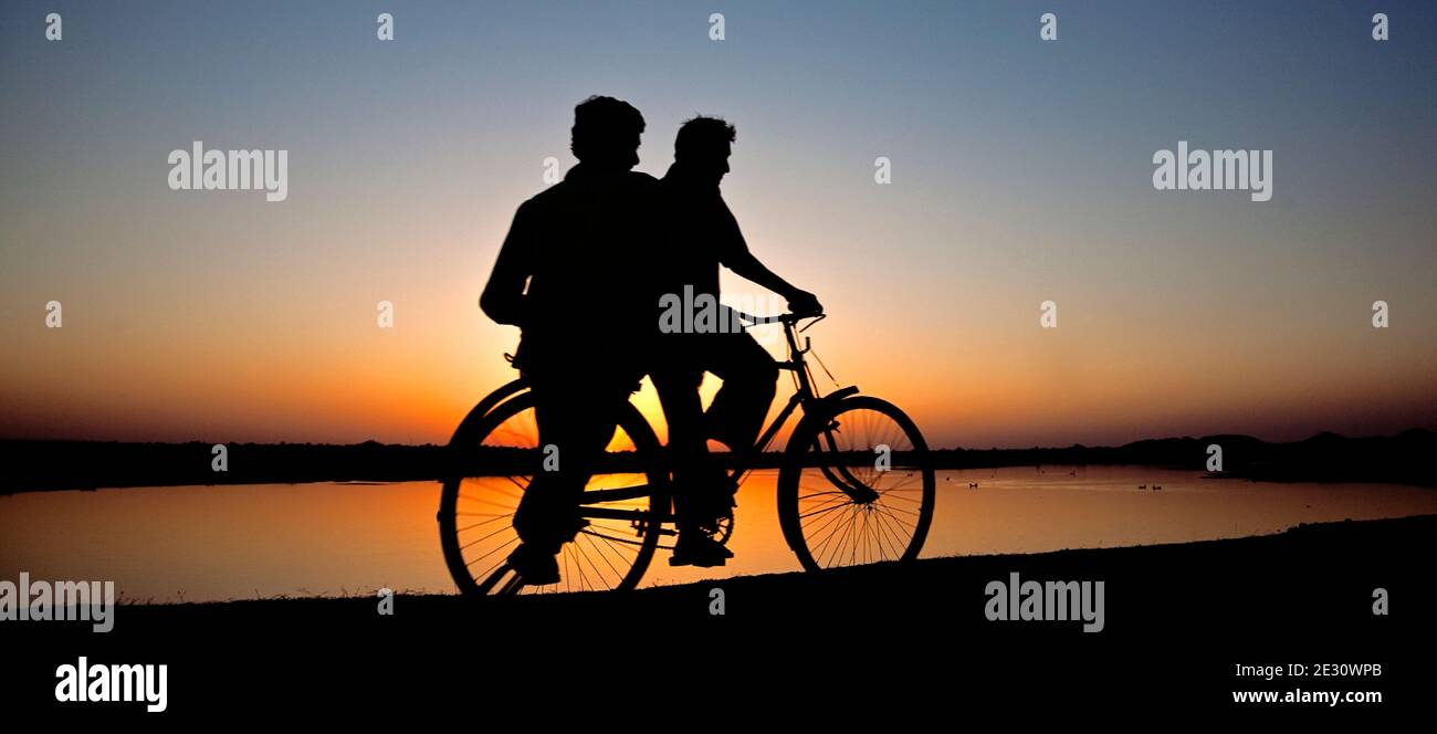 Uomini indiani in bicicletta a Sunset.Benisagar Reservoir.Mahya Pradesh.India Foto Stock