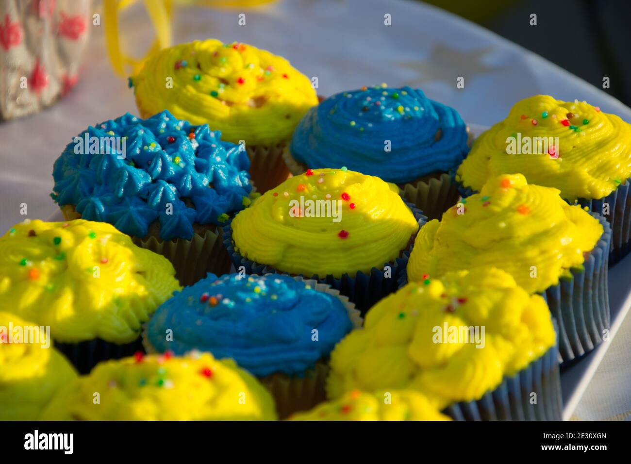 Cupcake fatti in casa colorati blu e gialli con spruzzi, minion Concept party, dessert in blu e giallo su un tavolo Foto Stock