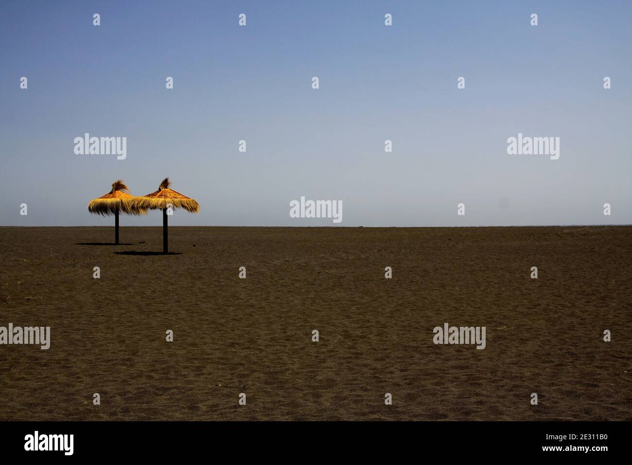 Vista panoramica su una spiaggia vuota e deserta con due paglia isolata ombrelli di paglia - il concetto di previsione di prognosi dell'industria turistica Foto Stock