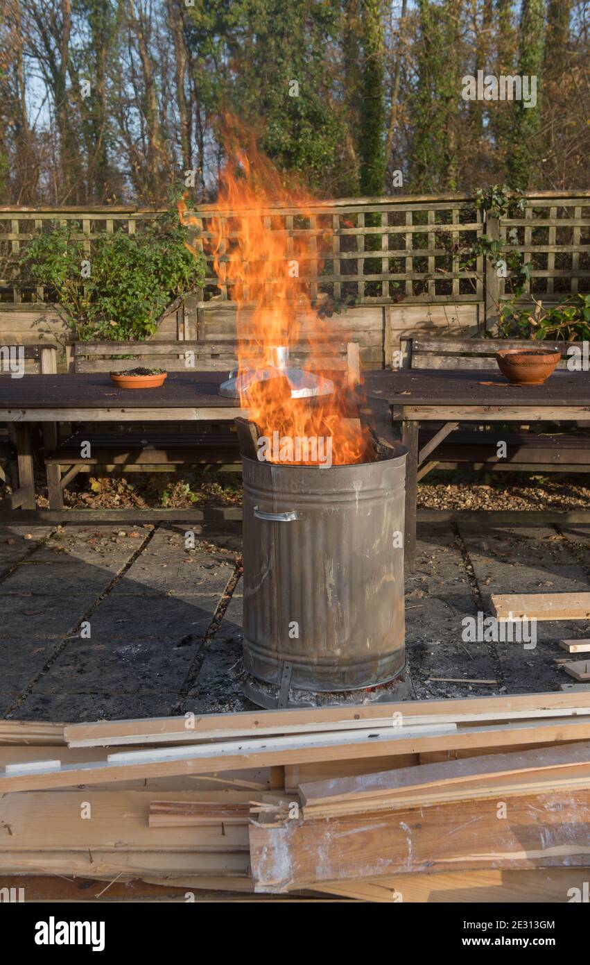 Legno bruciare in un inceneritore di acciaio galvanizzato in un giardino in Devon rurale, Inghilterra, Regno Unito Foto Stock