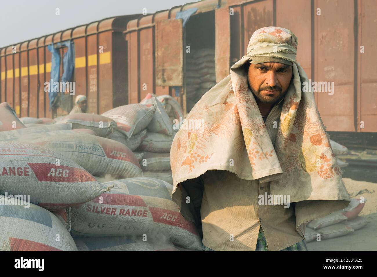 Uomo che indossa solo sciarpa per la testa come protezione impiegata per spostare sacchi di cemento da treno a camion a Mathura, Uttar Pradesh, India. Foto Stock