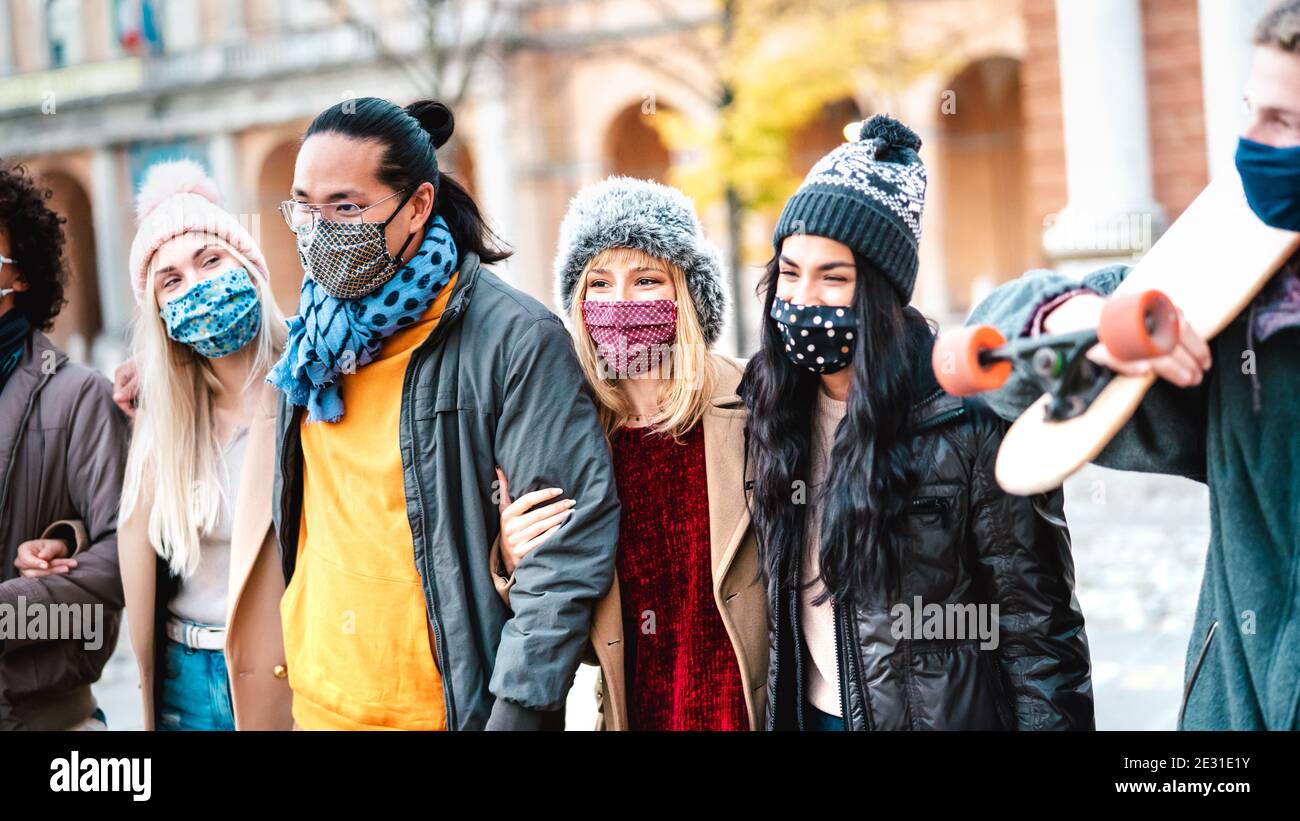 Gente mileniale urbana che cammina insieme indossando la maschera facciale in città Centro - nuovo concetto di stile di vita normale con amici multiculturali moda invernale Foto Stock