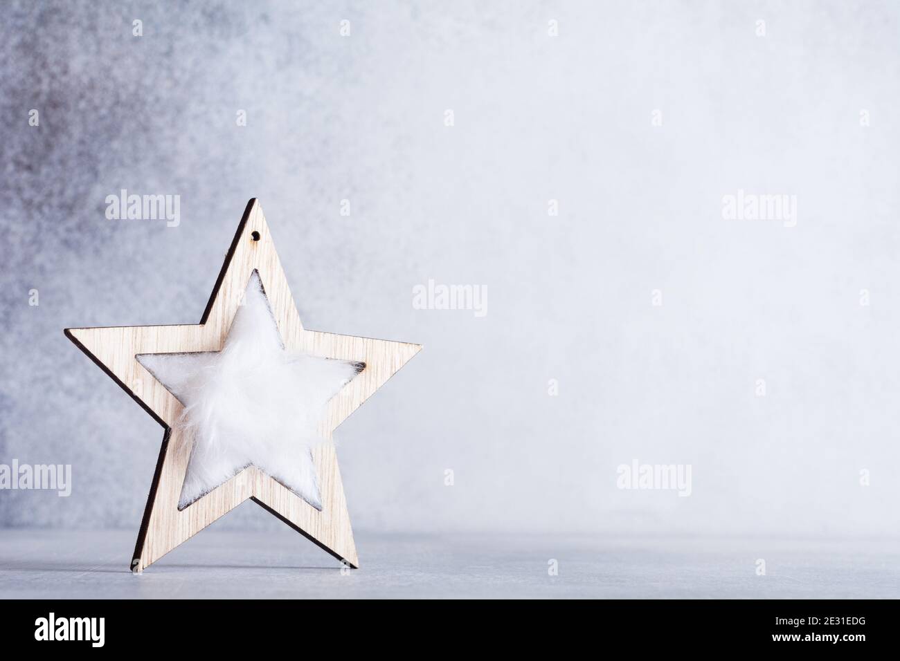 Sfondo natalizio con stella in legno su sfondo grigio chiaro. Eco-friendly, Natale senza sprechi. Foto Stock
