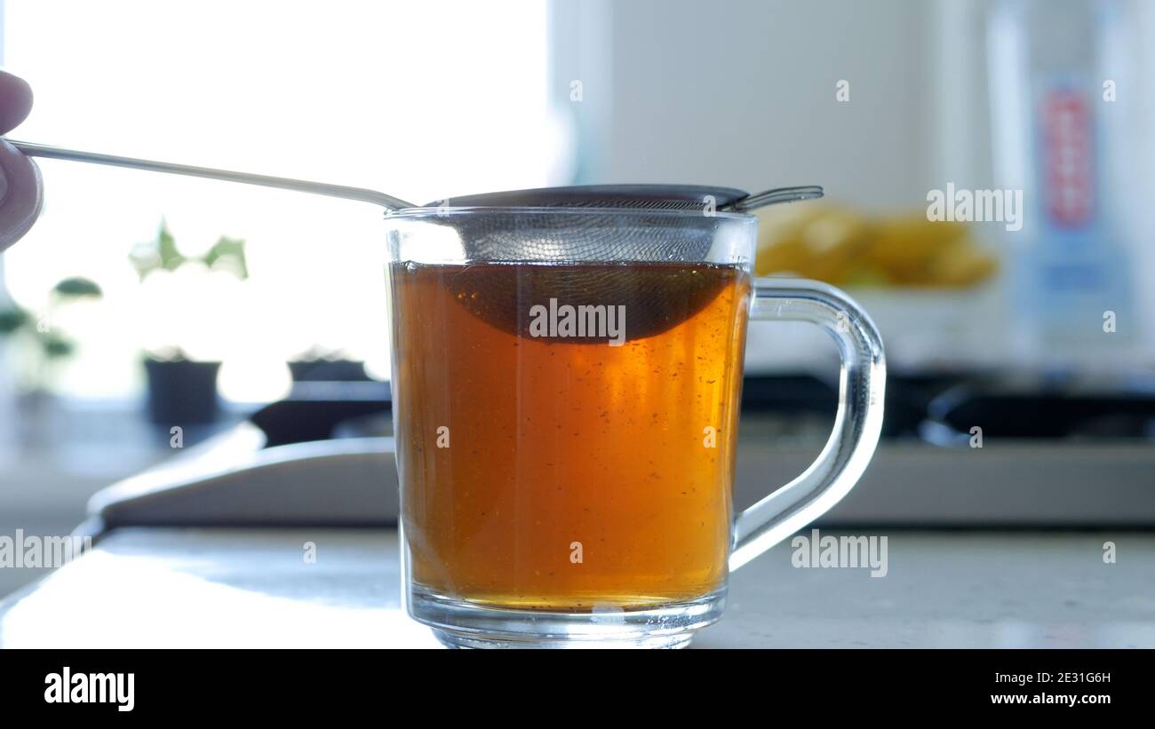 Immagine con la preparazione di un tè caldo e aromatico utilizzando un Succhieruola e foglie di tè naturale Foto Stock