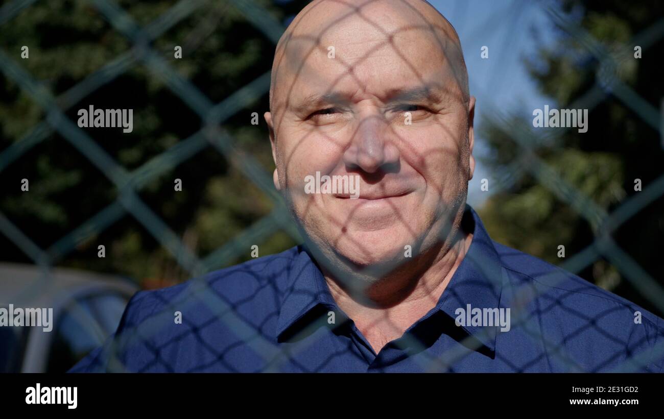 Immagine con una persona anziana dietro un Fence metallico sorridente Felice Foto Stock