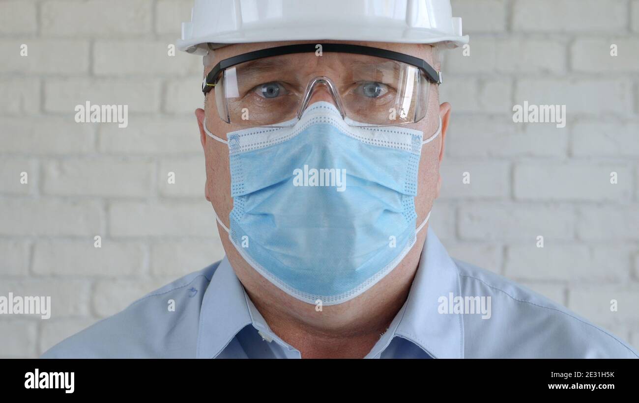 Ingegnere Ritratto indossare Hardhat, occhiali protettivi e maschera medica viso in Coronavirus Pandemic Foto Stock