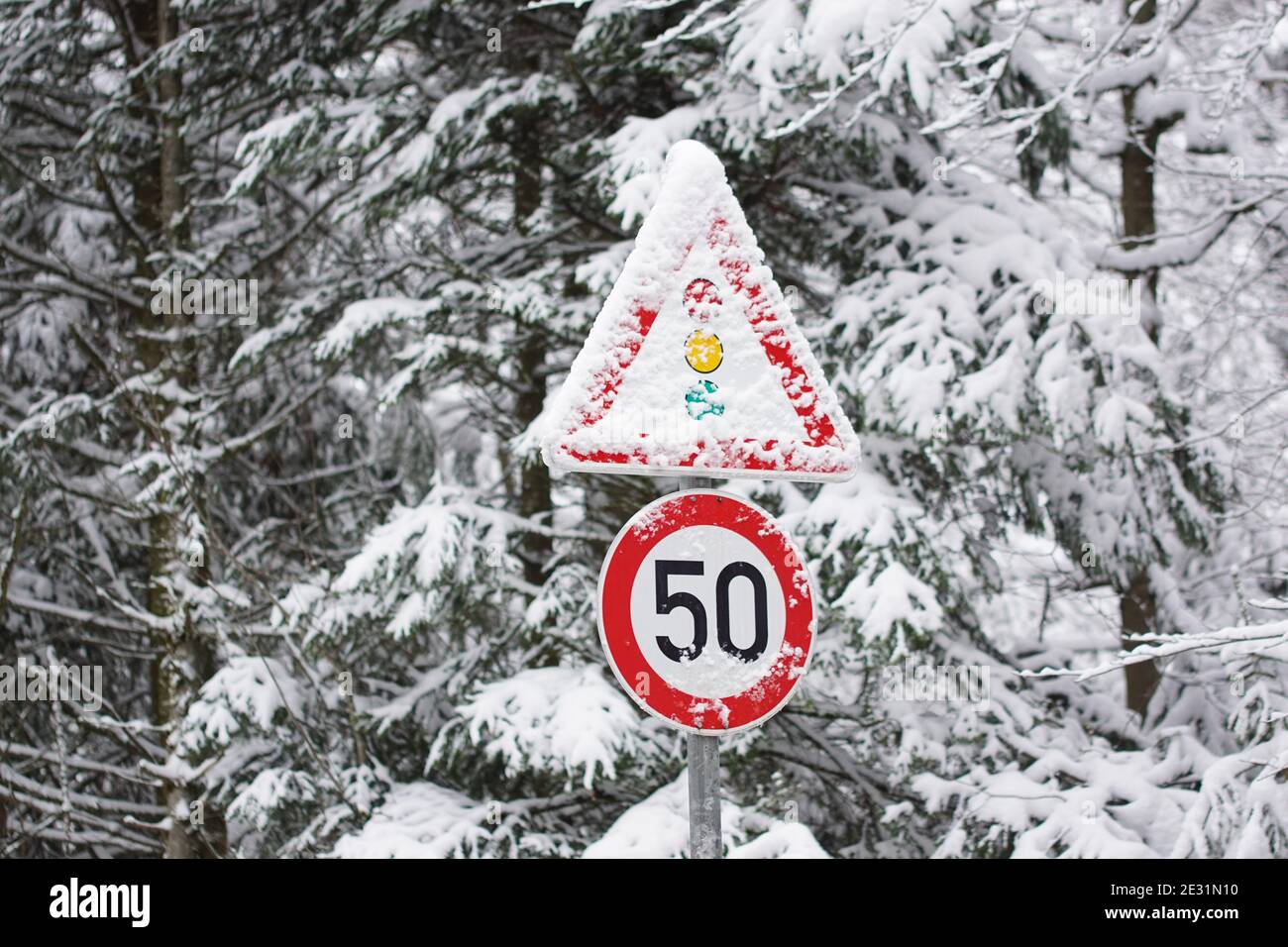 segnaletica stradale innevata in inverno, limite di velocità 50 e semaforo di attenzione Foto Stock
