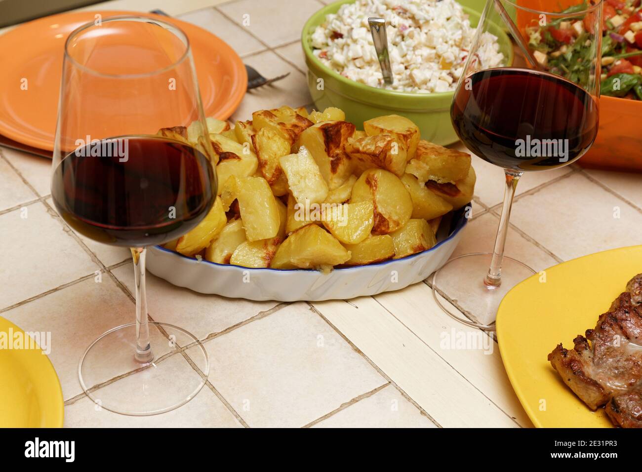 Piatto di patate alla griglia su un tavolo vicino a a. bicchieri di vino rosso Foto Stock