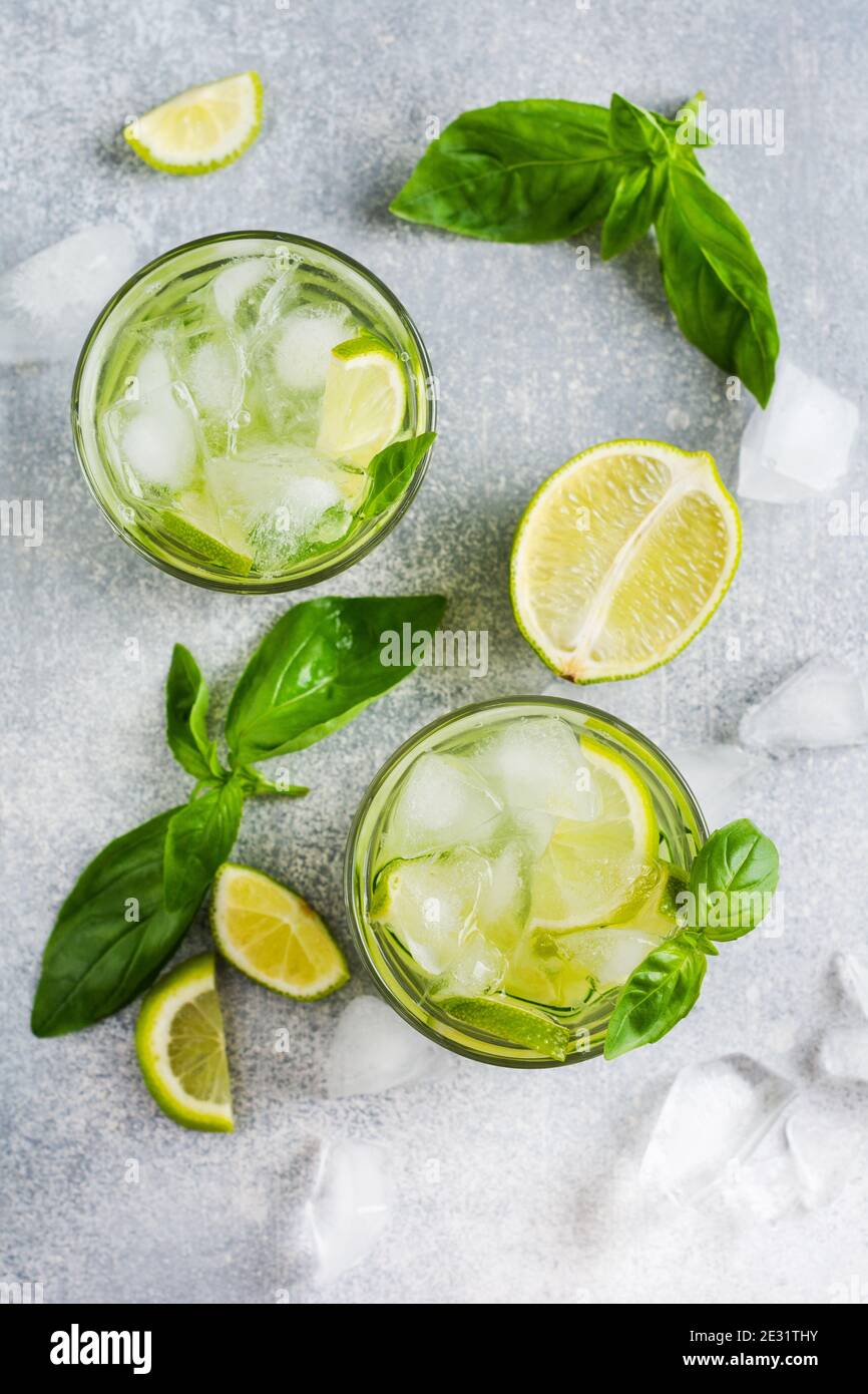 Limonata estiva fatta in casa da lime, limone, cetriolo e basilico con ghiaccio in vetro su un vecchio fondo di cemento. Messa a fuoco selettiva. Foto Stock