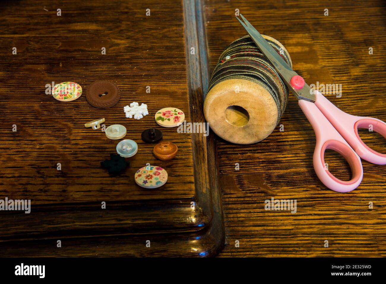 Bottoni, forbici e ricrac sulla parte superiore di una macchina da cucire d'epoca. Oggetti ordinari, vita quotidiana, con colori e texture. Foto Stock