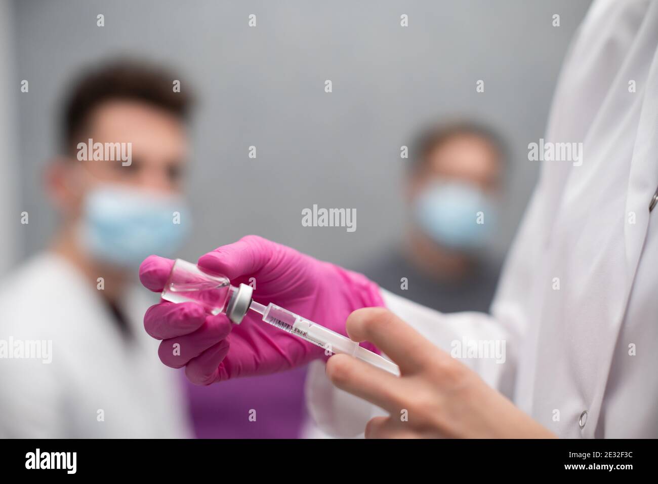 In una lezione pratica, un giovane infermiere mostra ai medici in formazione come prelevare correttamente un medicinale da un flaconcino utilizzando una siringa. Un'iniezione con una nuova formulazione di vaccino contro COVID19 e altre malattie infettive in questo gruppo. Foto Stock