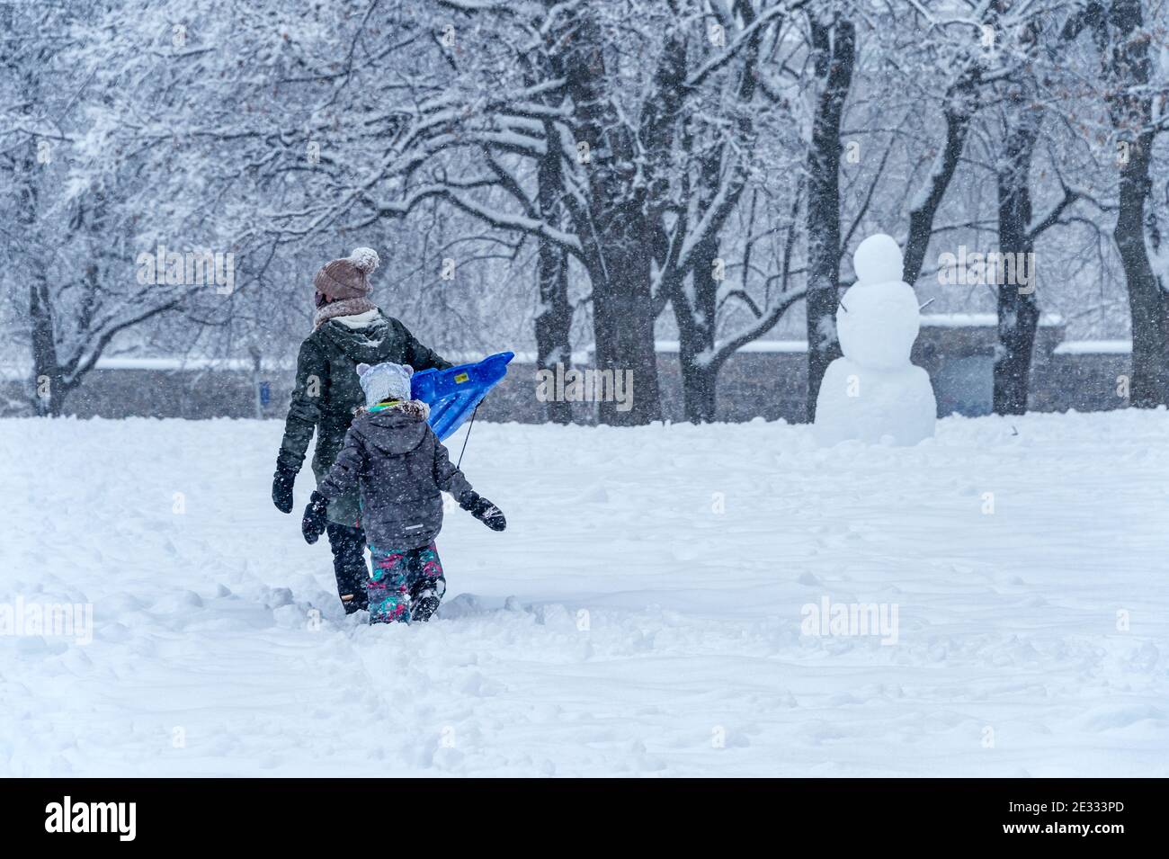 Montreal, QC, Canada - 16 Gennaio 2021: Madre e bambino camminano nel parco Jeanne-Mance durante la tempesta di neve. Foto Stock
