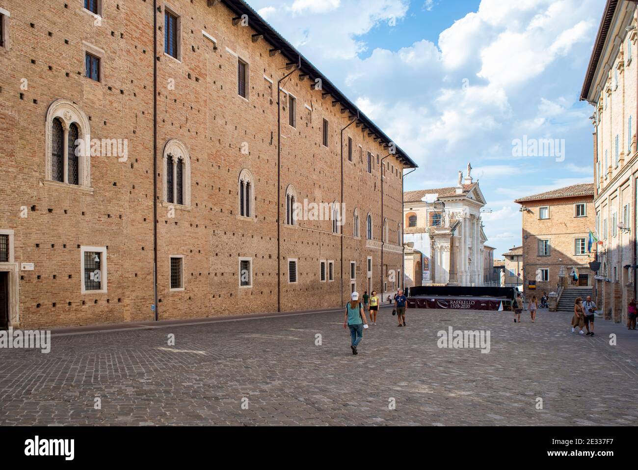 Donna che cammina da sola in una piazza n Urbino, famosa città medievale in Italia Foto Stock