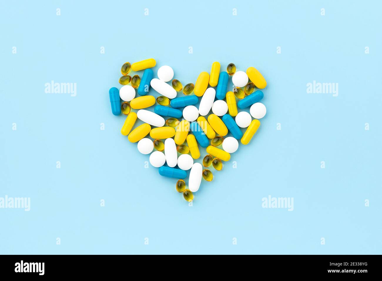 Pillole mediche a forma di cuore su sfondo blu Foto Stock
