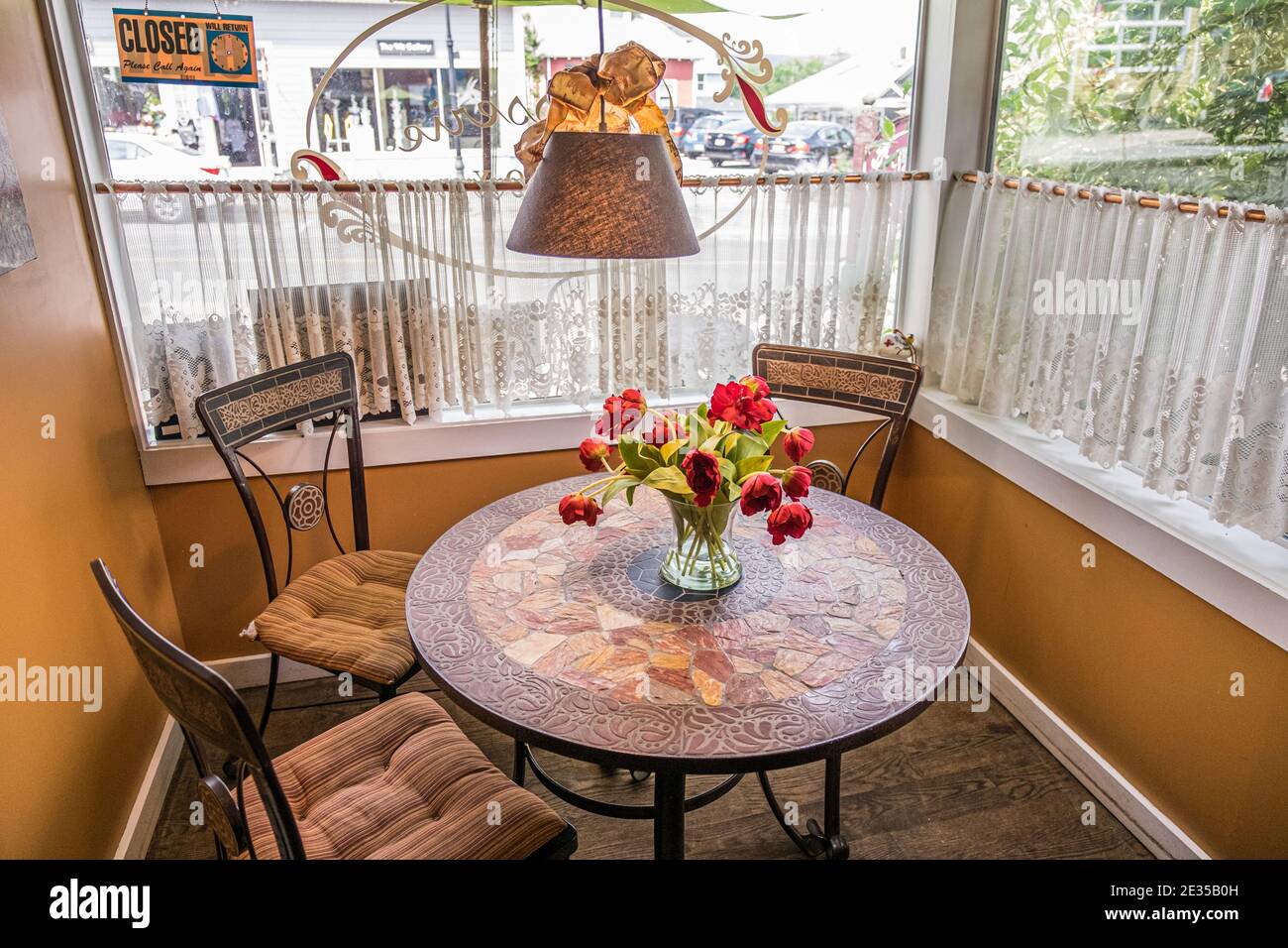 Un piccolo tavolo con fiori rossi in un caffè Lenox, Massachusetts - la Patisserie Foto Stock