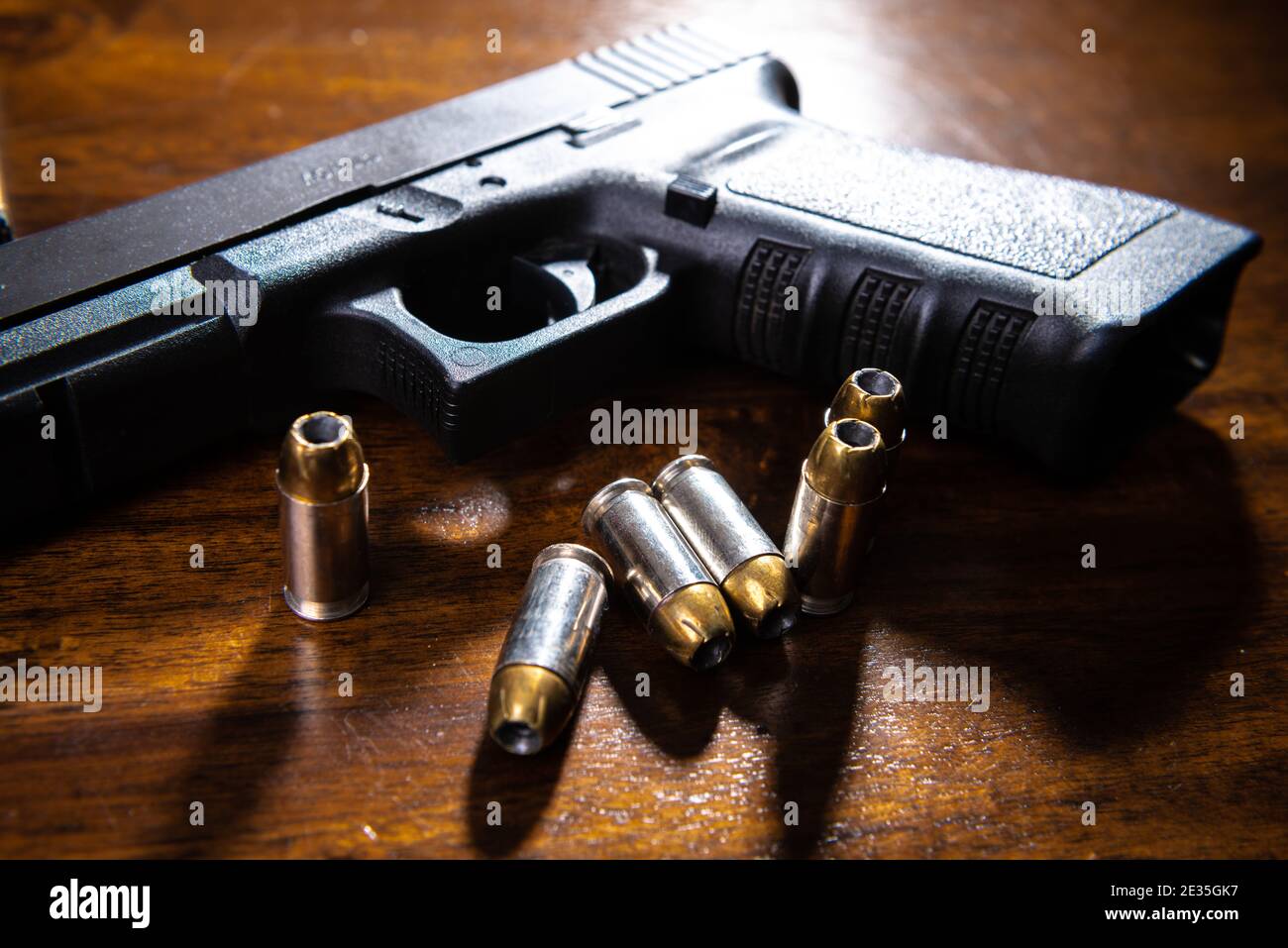 Una pistola semiautomatica nera e munizioni su un tavolo di legno. Foto Stock