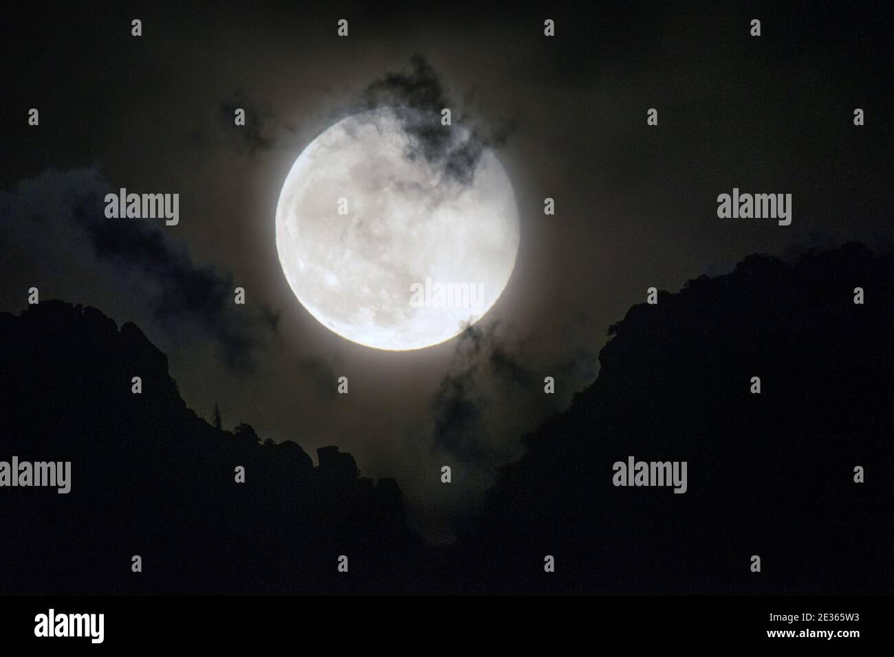Luna piena che si erge sulle montagne del deserto Foto Stock