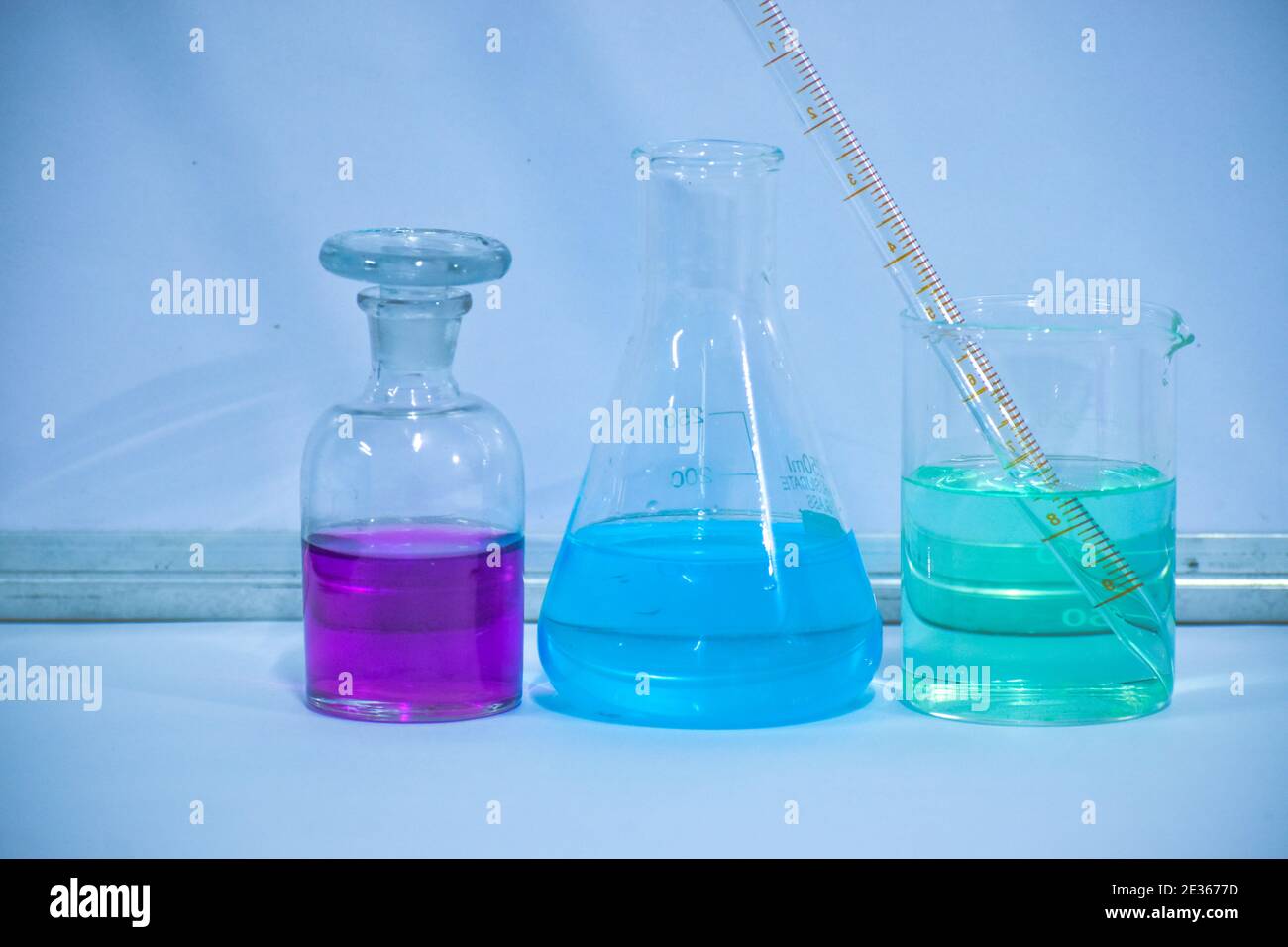 Soluzione di colore in laboratorio chimico. Apparecchiatura per laboratorio chimico con soluzione a colori. Flacone di reagente, matraccio conico e becher. Foto Stock