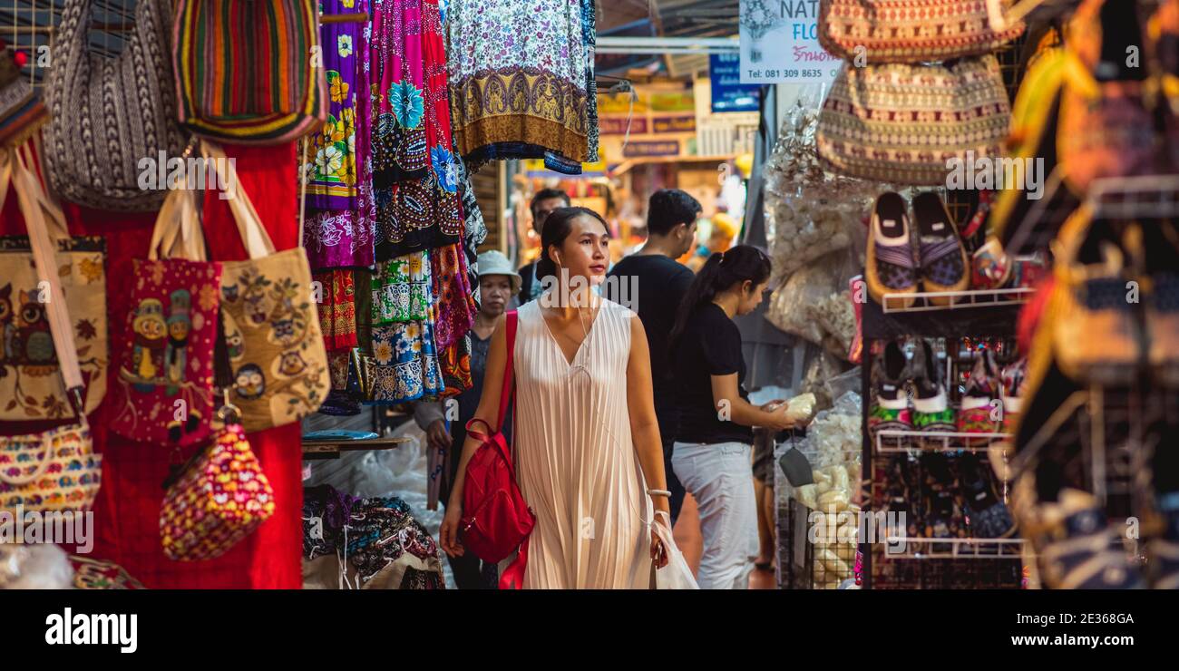 Bangkok, Thailandia - 14 maggio 2017: Giovane donna asiatica (non identificata) cammina con le cuffie lungo le bancarelle e gli stand del mercato Chatuchak. Foto Stock