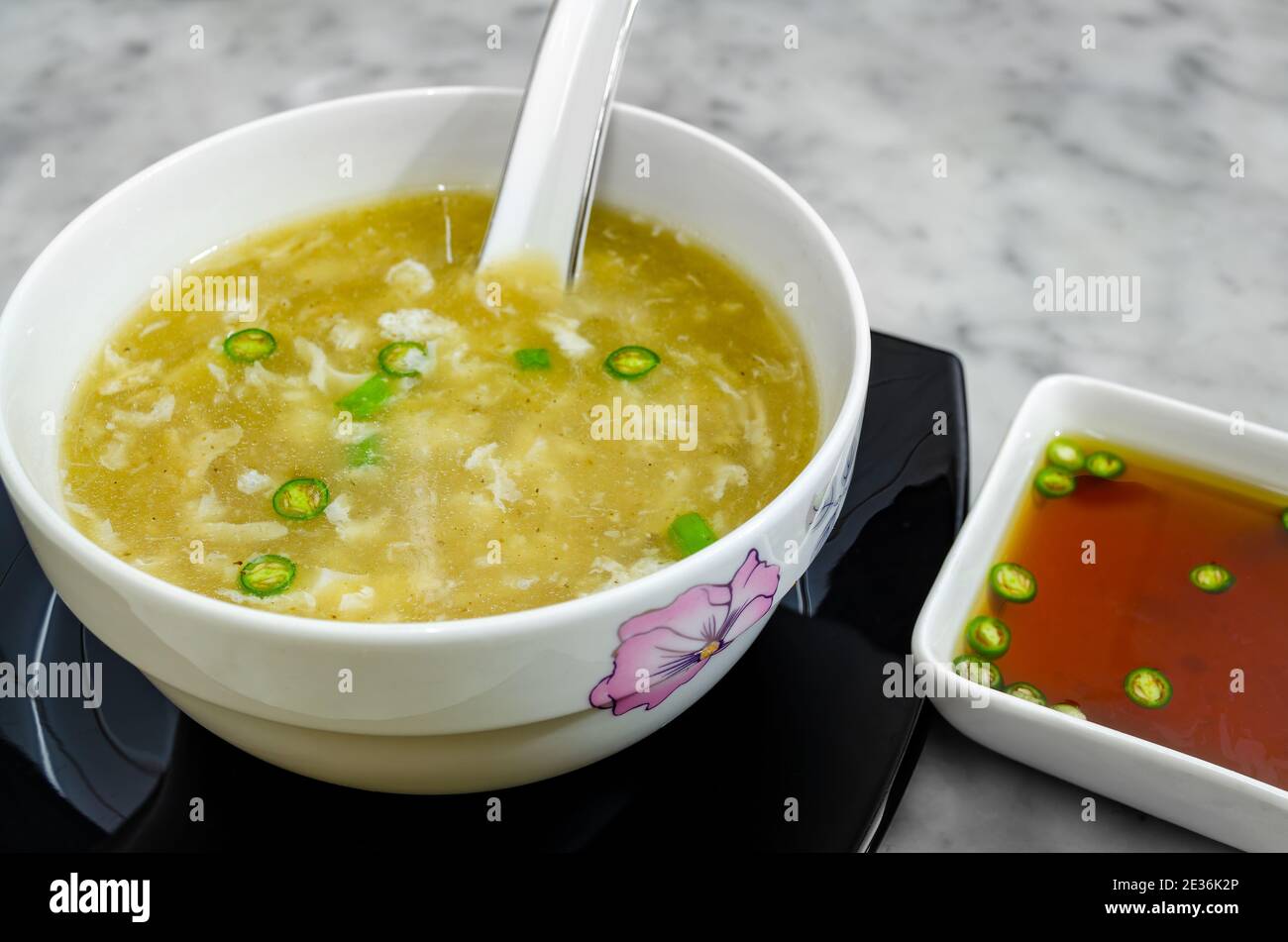 Zuppa di pollo calda in un recipiente insieme a una zuppa piccante salsa di chili da accompagnare Foto Stock
