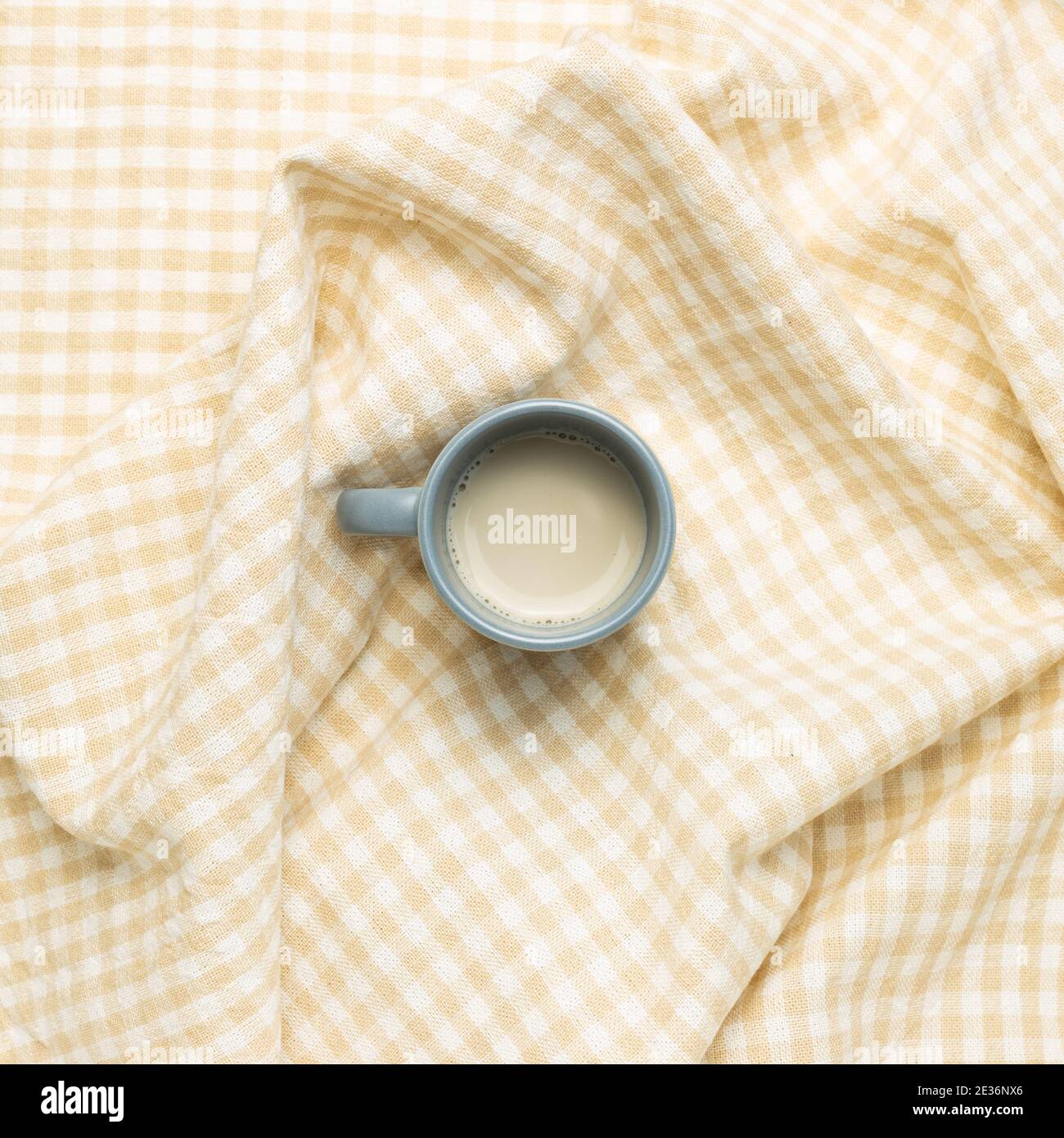 Tazza di tè al latte su fondo in tessuto beige crumpled check pattern. Vista dall'alto Foto Stock