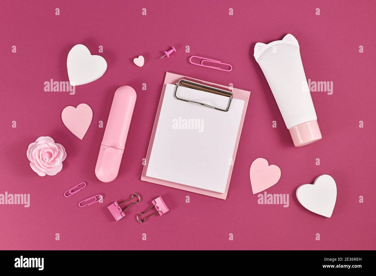 Appunti con carta vuota per testo circondato da cuori, prodotti di bellezza e articoli di cancelleria su sfondo rosa scuro Foto Stock