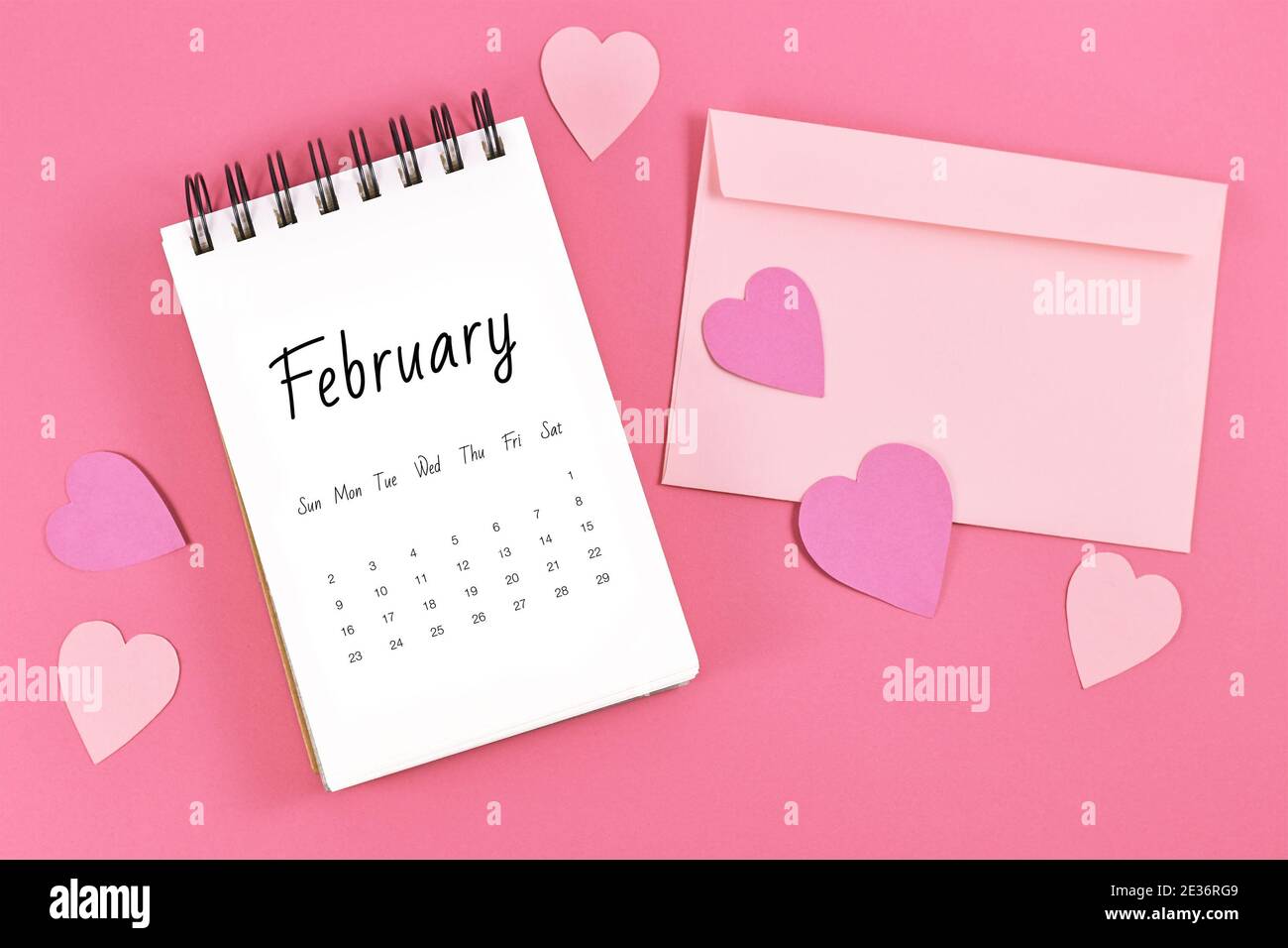 Piatto Lay con foglio di calendario di febbraio con San Valentino in su il 14 circondato da cuori e lettera d'amore su rosa sfondo Foto Stock