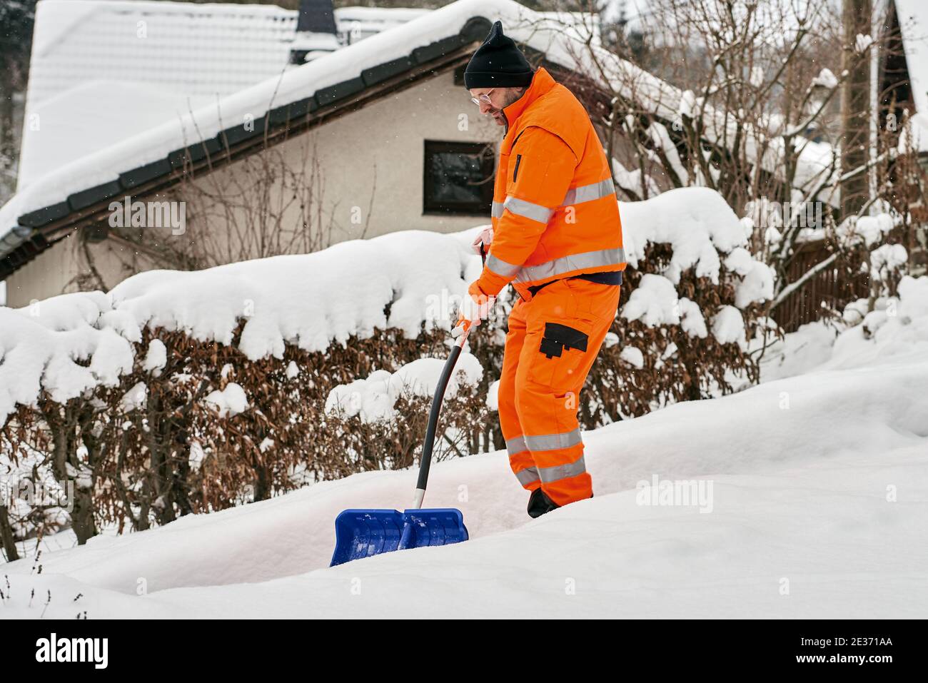 Operaio di servizio comunale in uniforme con una pala libera la neve in inverno Foto Stock