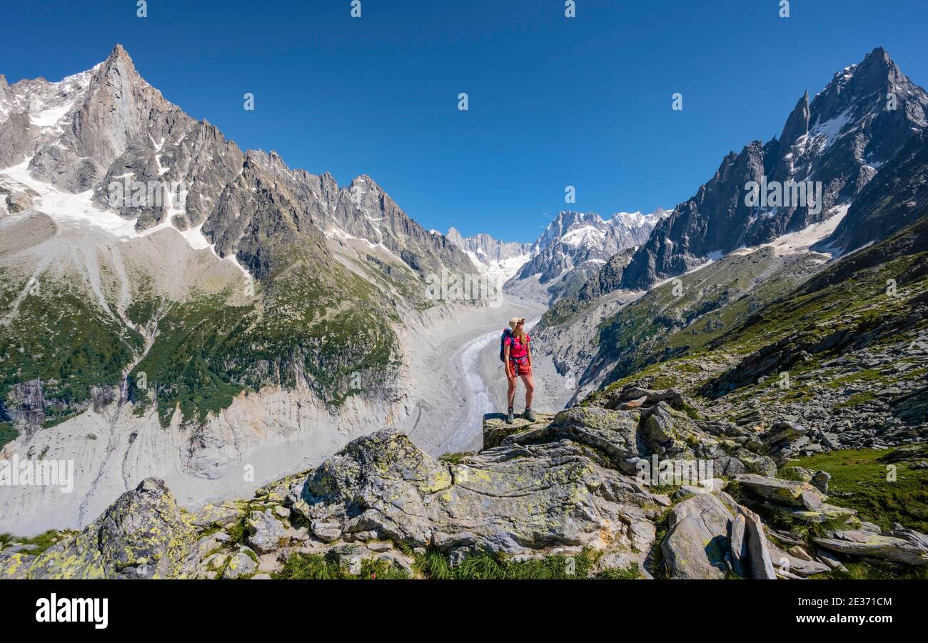 Scalatore in piedi su rocce, Grand Balcon Nord, lingua del ghiacciaio Mer de Glace, dietro Grandes Jorasses, massiccio del Monte Bianco, Chamonix, Francia Foto Stock
