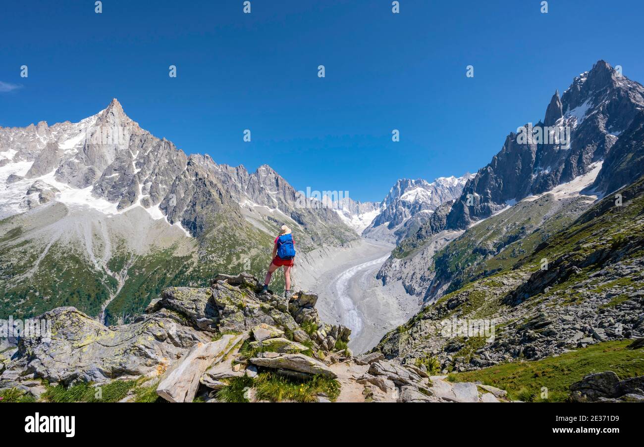 Scalatore in piedi su rocce, Grand Balcon Nord, lingua del ghiacciaio Mer de Glace, dietro Grandes Jorasses, massiccio del Monte Bianco, Chamonix, Francia Foto Stock