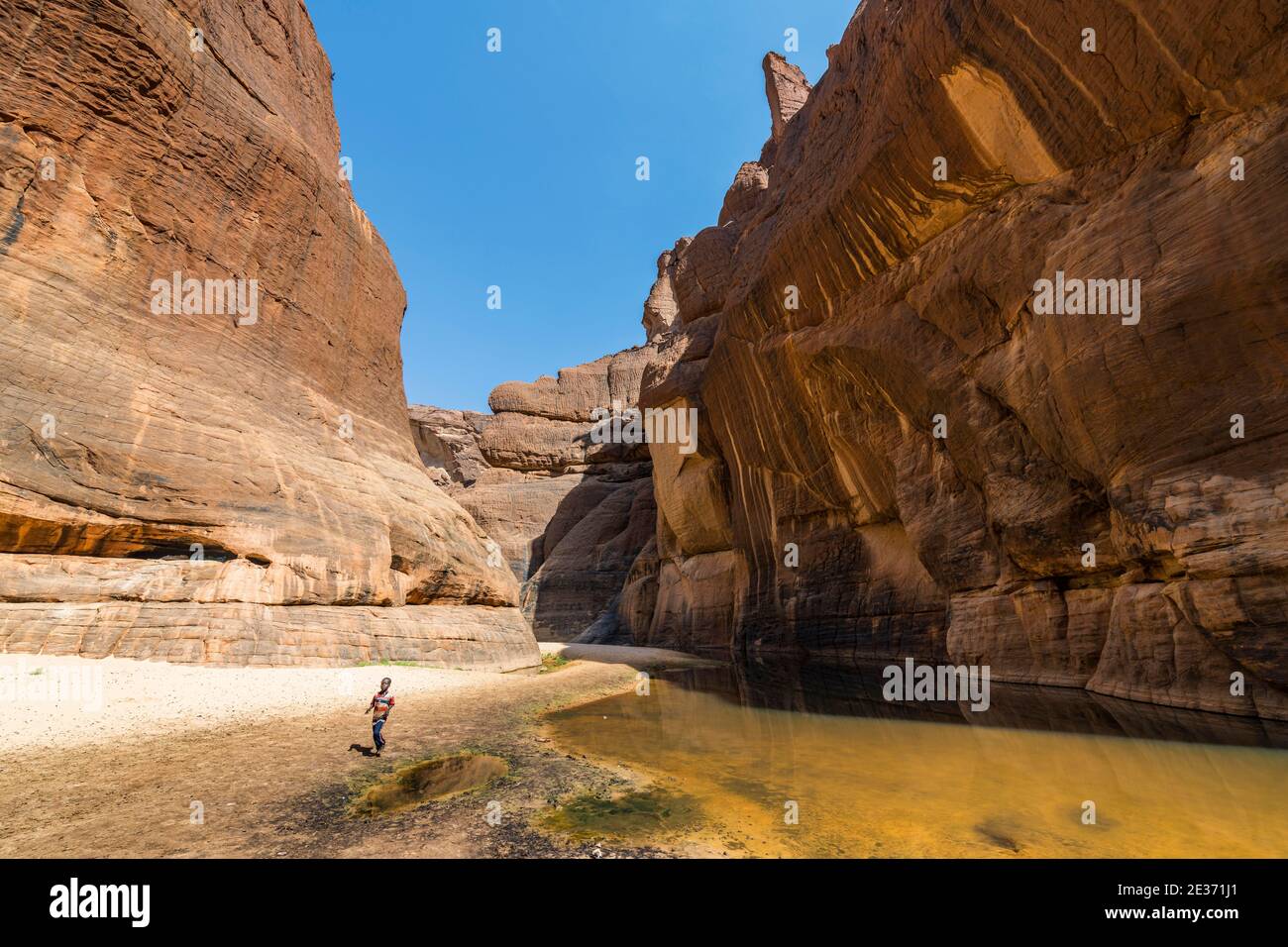 Ragazzo al buco d'acqua Guelta d'Archei, gola di roccia, altopiano Ennedi, Ciad Foto Stock