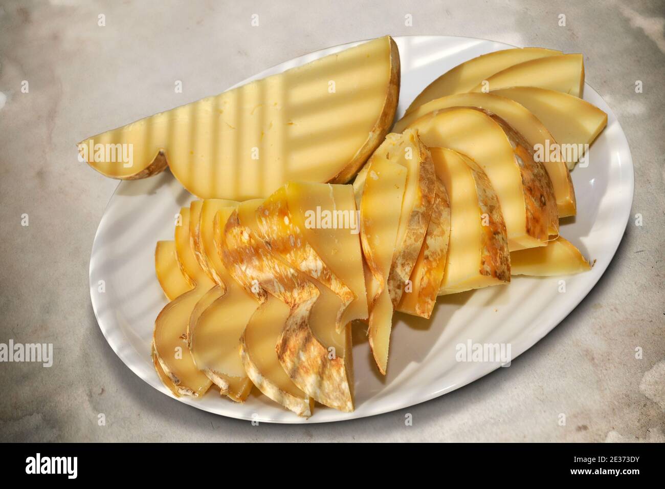 Caciocavallo italiano condito, fette di tipico formaggio pugliese in piatto bianco su fondo punteggiato, vista dall'alto Foto Stock