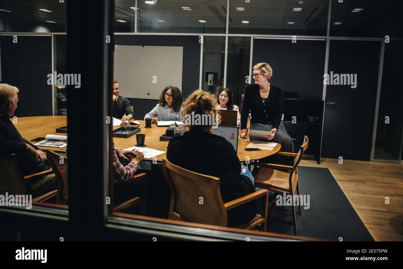 Team aziendale creativo nella sala riunioni dell'ufficio. Gruppo di uomini d'affari diversi che hanno una riunione all'interno della sala conferenze. Foto Stock