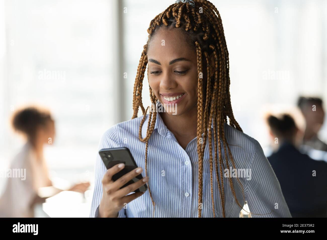Sorridente donna etnica utilizzare smartphone SMS on-line Foto Stock