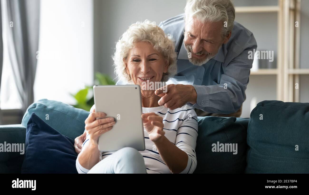 Una coppia di anziani di mezza età allegra ed emotiva che utilizza un tablet digitale. Foto Stock