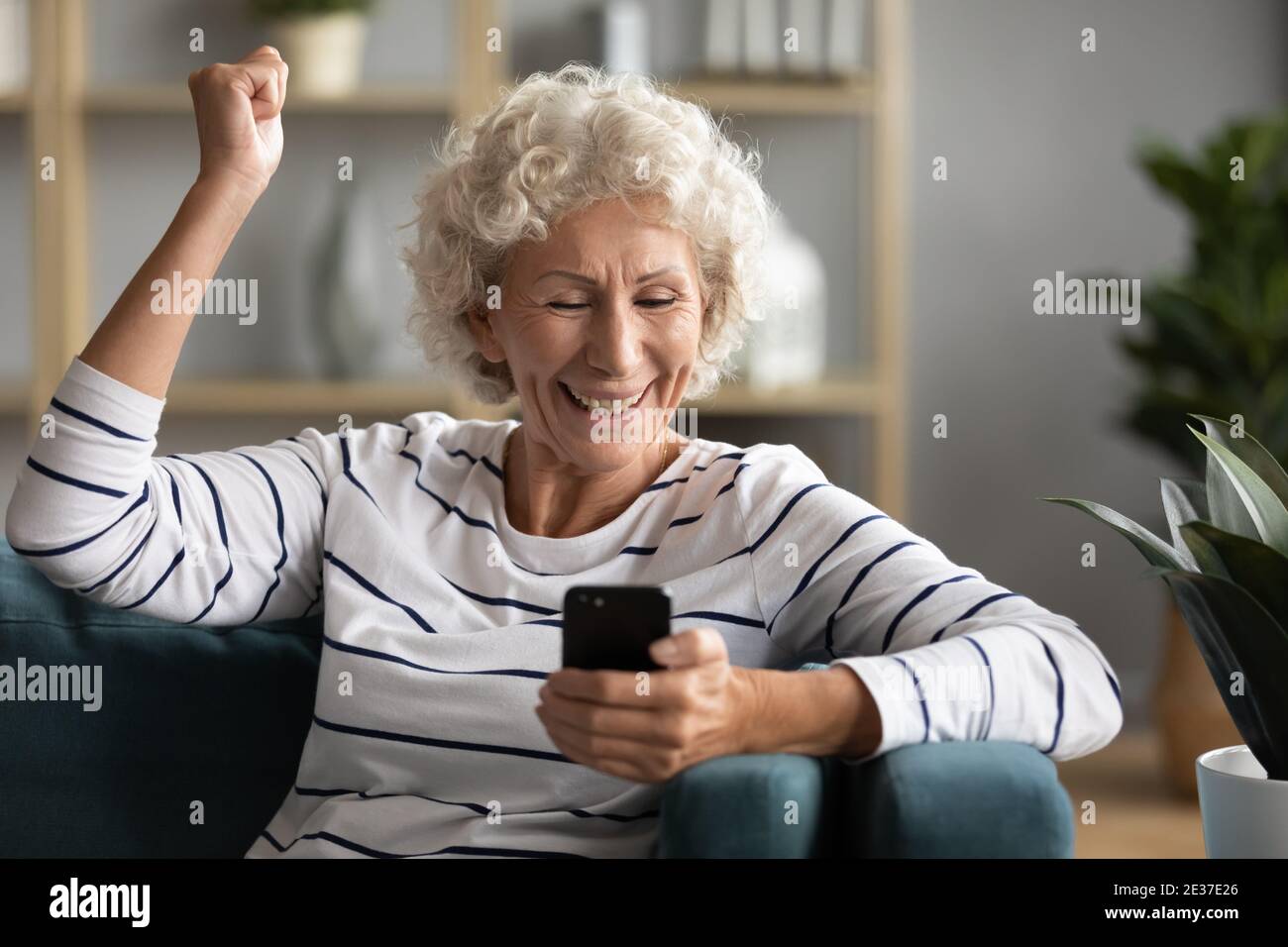 Felice emozionale vecchia donna caucasica celebrando il successo online. Foto Stock