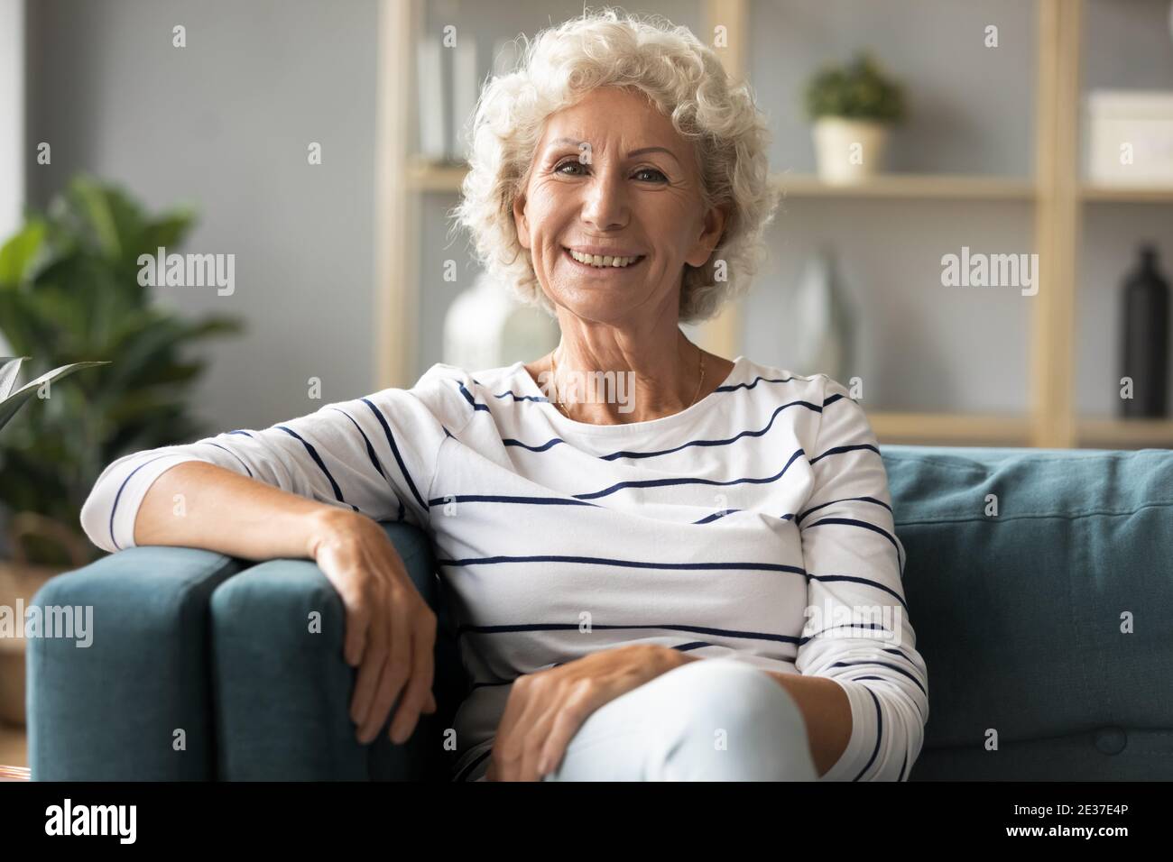 Ritratto di donna matura sorridente che si rilassa su un comodo divano. Foto Stock
