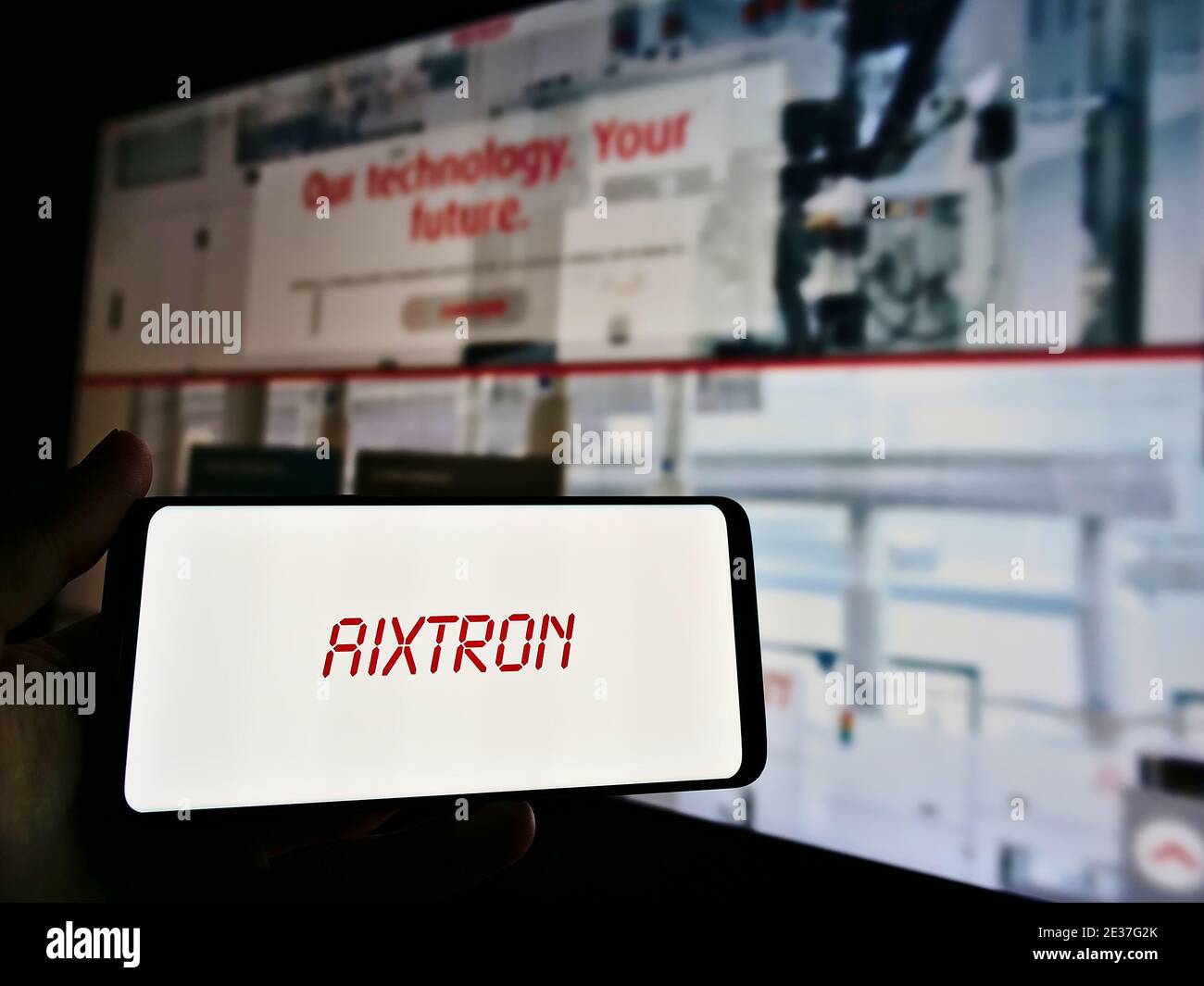 Titolare smartphone con logo della società tedesca Aixtron se nel settore dei semiconduttori. Mettere a fuoco lo schermo del telefono cellulare. Foto Stock